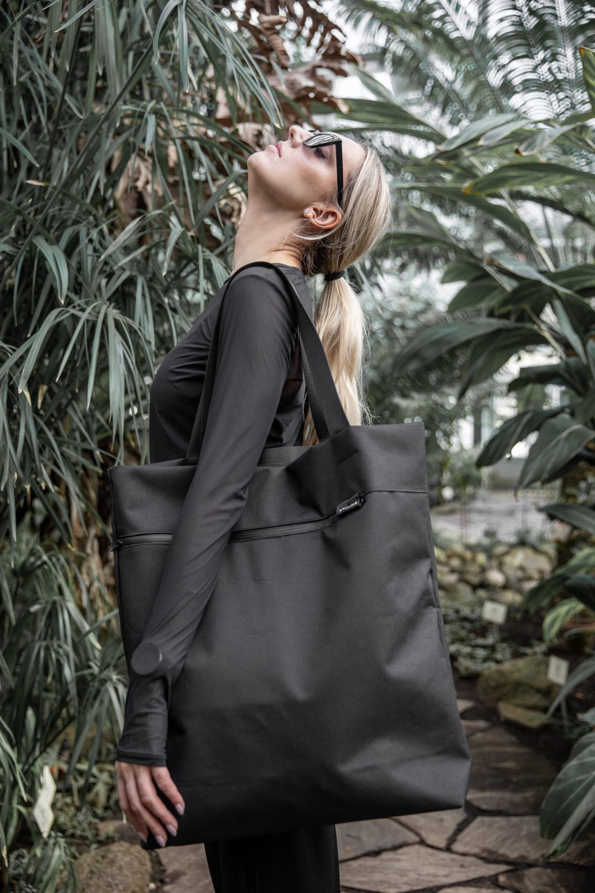15. Woman with Nordhale VIK Tote Bag in black, showcasing its spaciousness and modern look in a natural environment