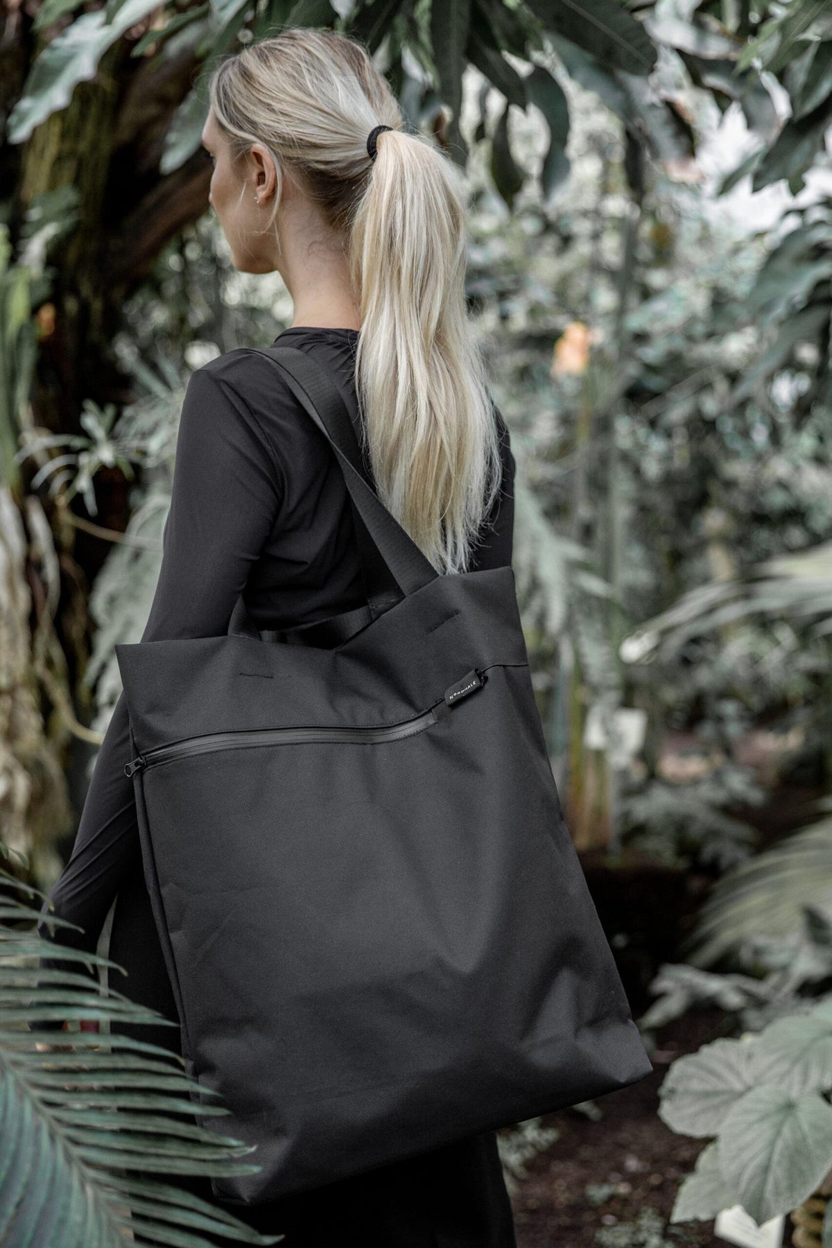 14. Woman with Nordhale VIK Tote Bag in black, highlighting its large size and elegant design in a garden setting