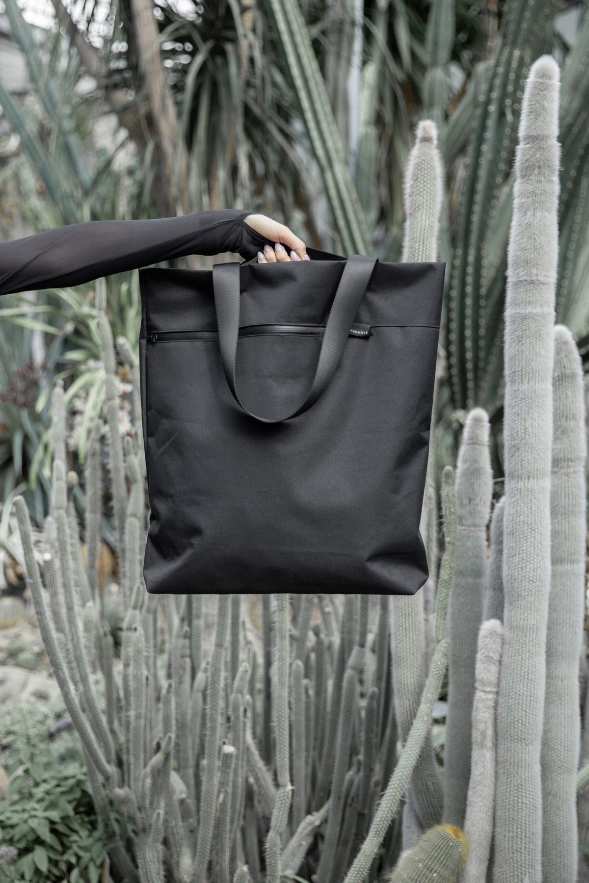 2. Nordhale VIK Tote Bag in black held by a woman, highlighting its sleek design against a natural backdrop