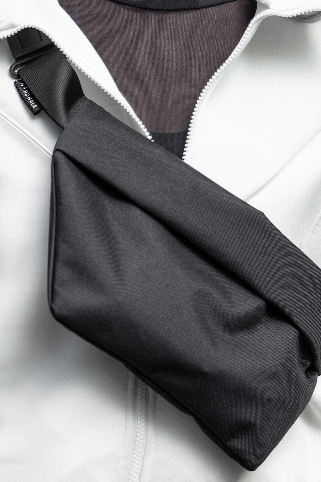 7. Close-up of Nordhale OSLO Cross Body Bag in black, worn over white jacket, showing fabric texture