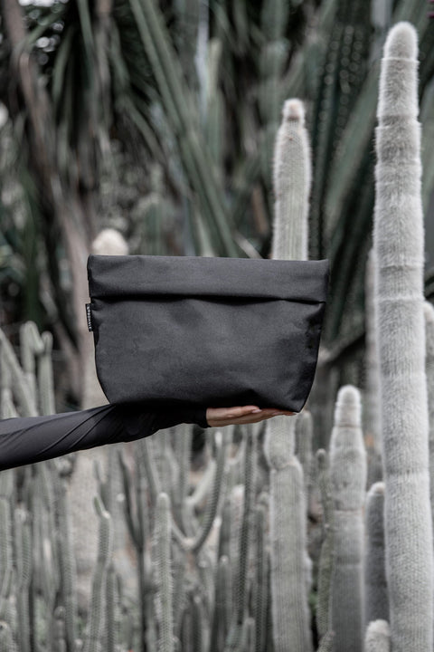 1. Nordhale NES Toiletry Bag in black held against a cactus background, showcasing minimalist design