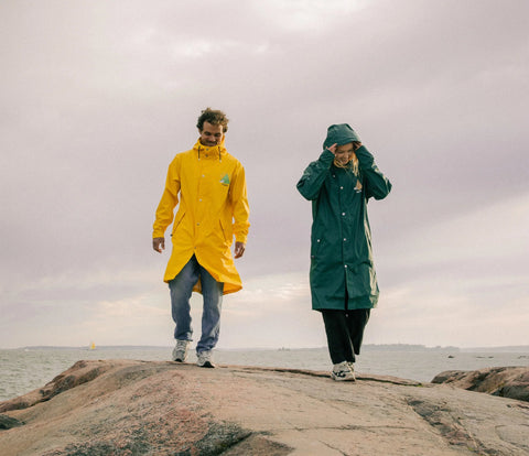 3. Unisex yellow and green Moomin Adventure Rain Jackets worn by models on rocky landscape