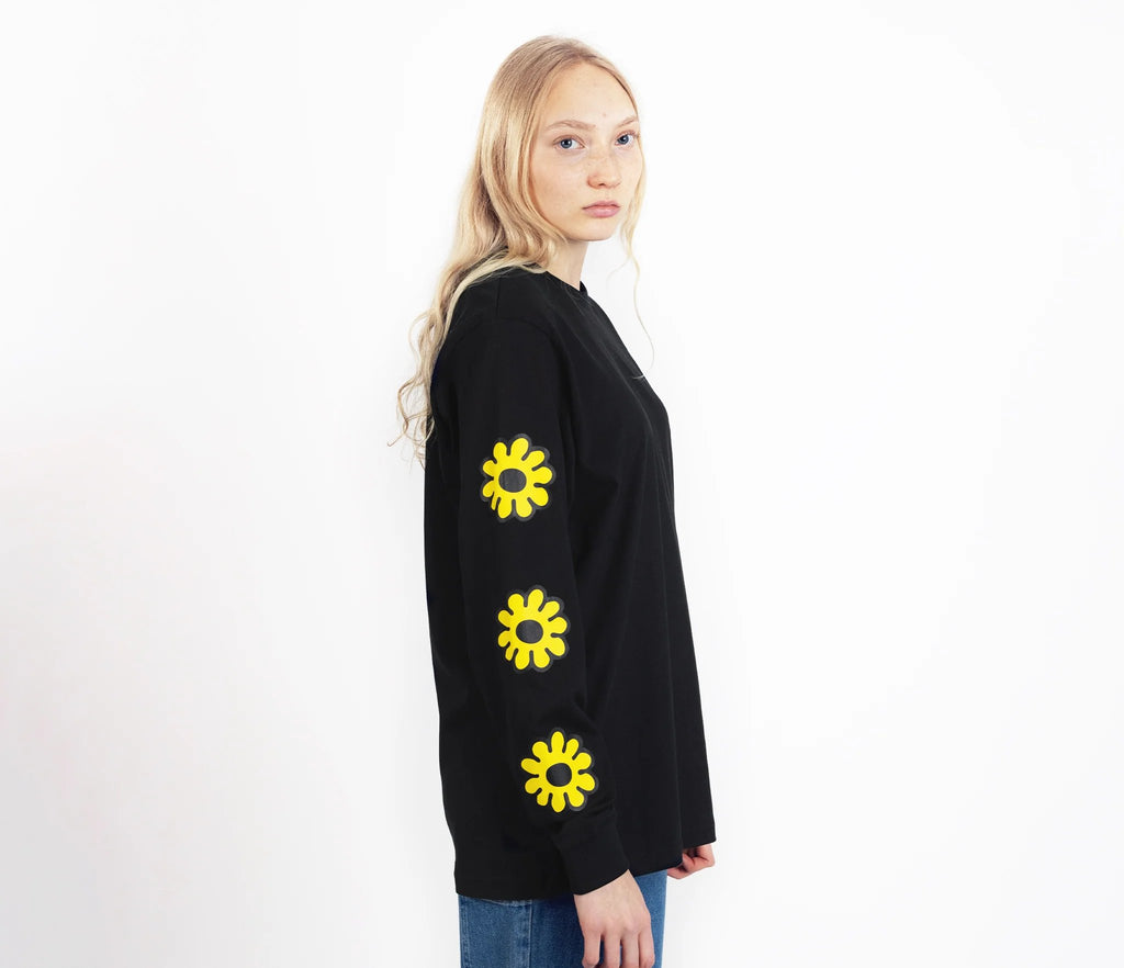 5. Unisex black Moomintroll's Flower longsleeve shirt worn by female model, side view highlighting yellow floral sleeve design