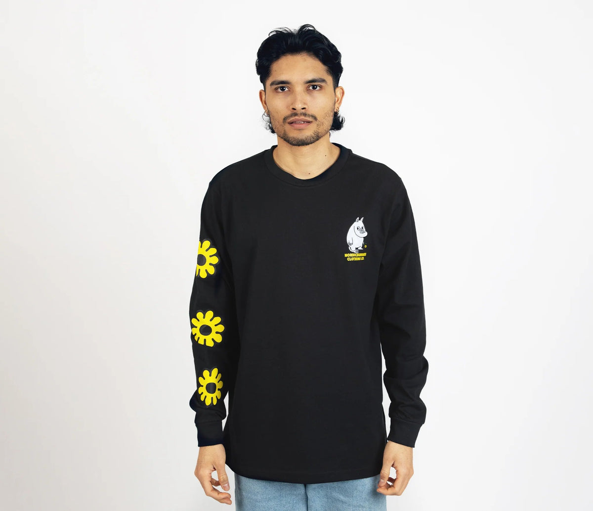 1. Unisex black Moomintroll's Flower longsleeve shirt worn by male model, featuring yellow floral sleeve design and Moomin logo, studio setting
