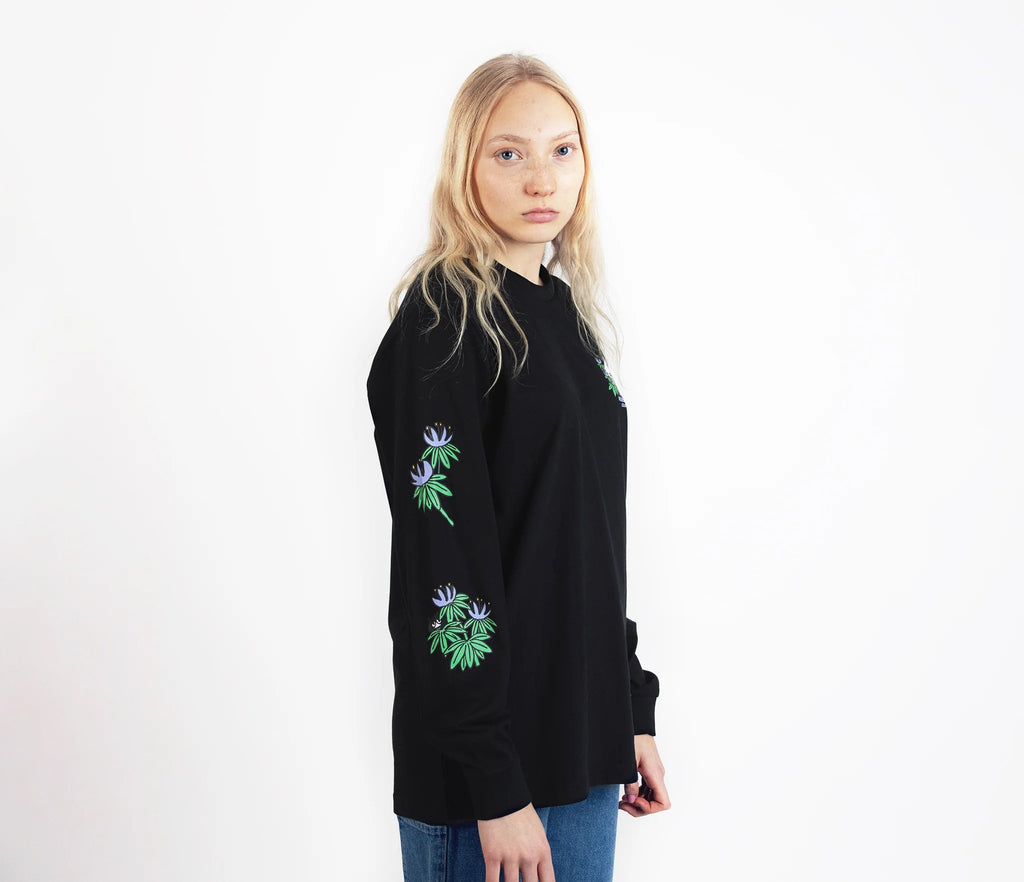 3. Female model wearing Moomin by NordicBuddies black longsleeve shirt with cuffrib, side view in studio