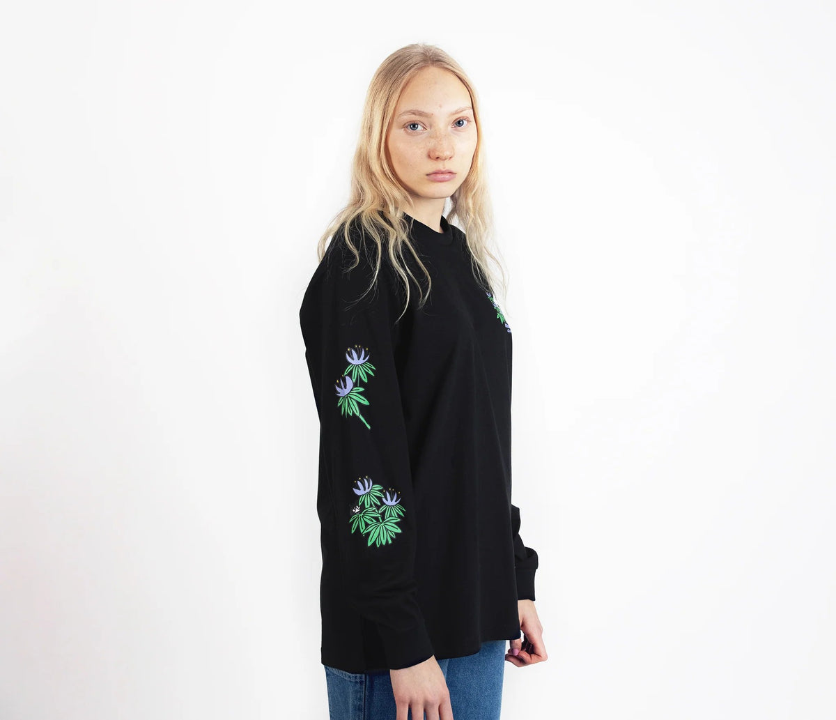 3. Female model wearing Moomin by NordicBuddies black longsleeve shirt with cuffrib, side view in studio
