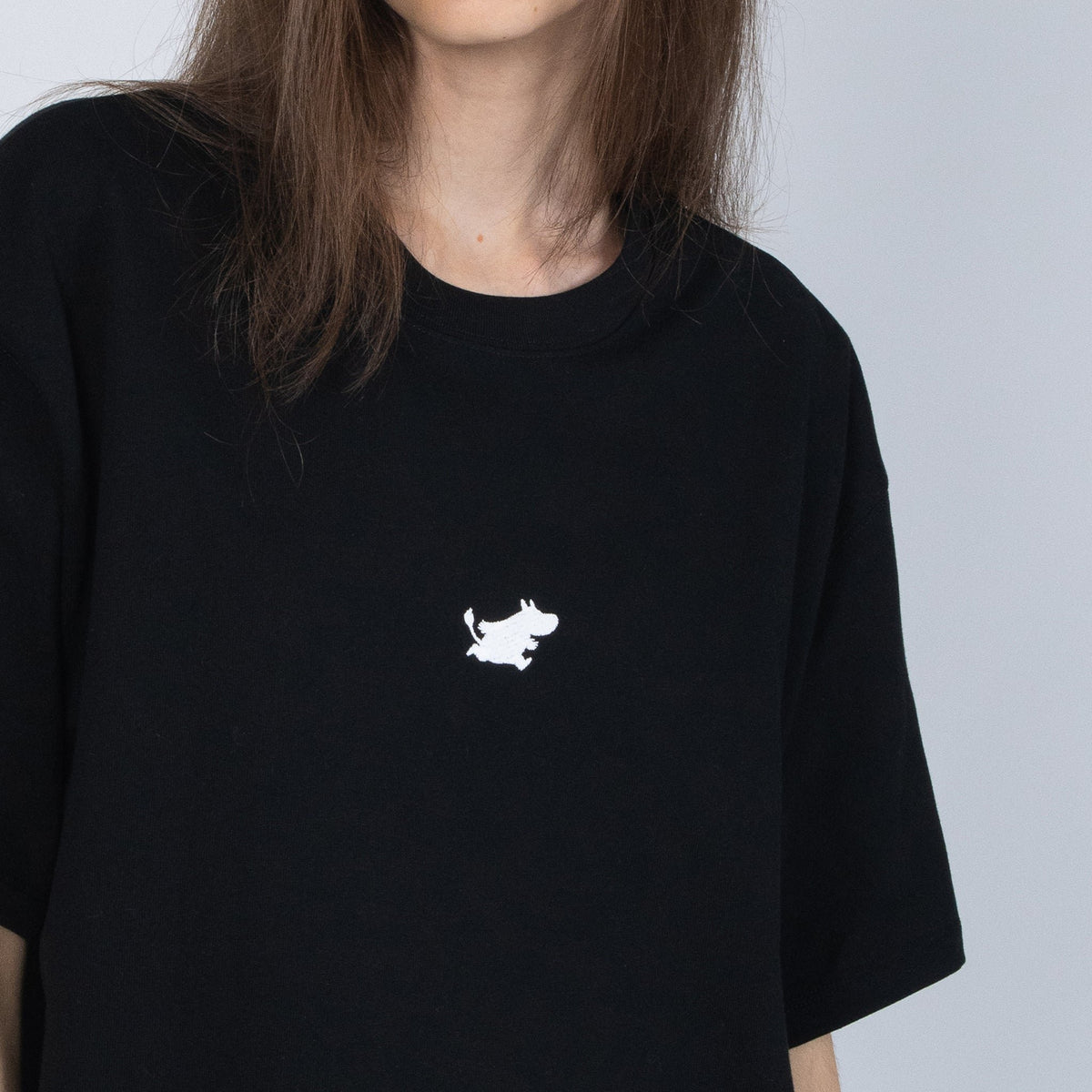 2. Close-up of black Moomin Classics t-shirt with white Moomin logo, worn by female model