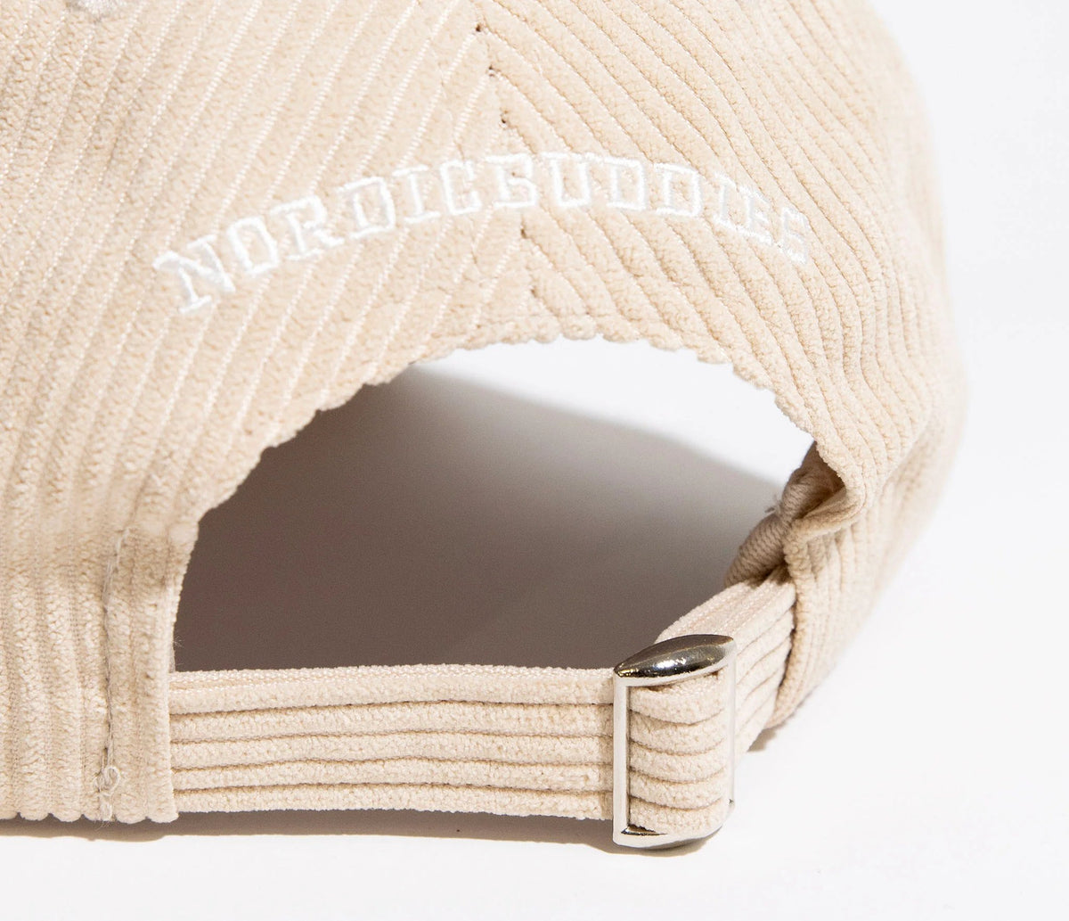 7. Close-up of adjustable strap and NordicBuddies branding on sand corduroy cap