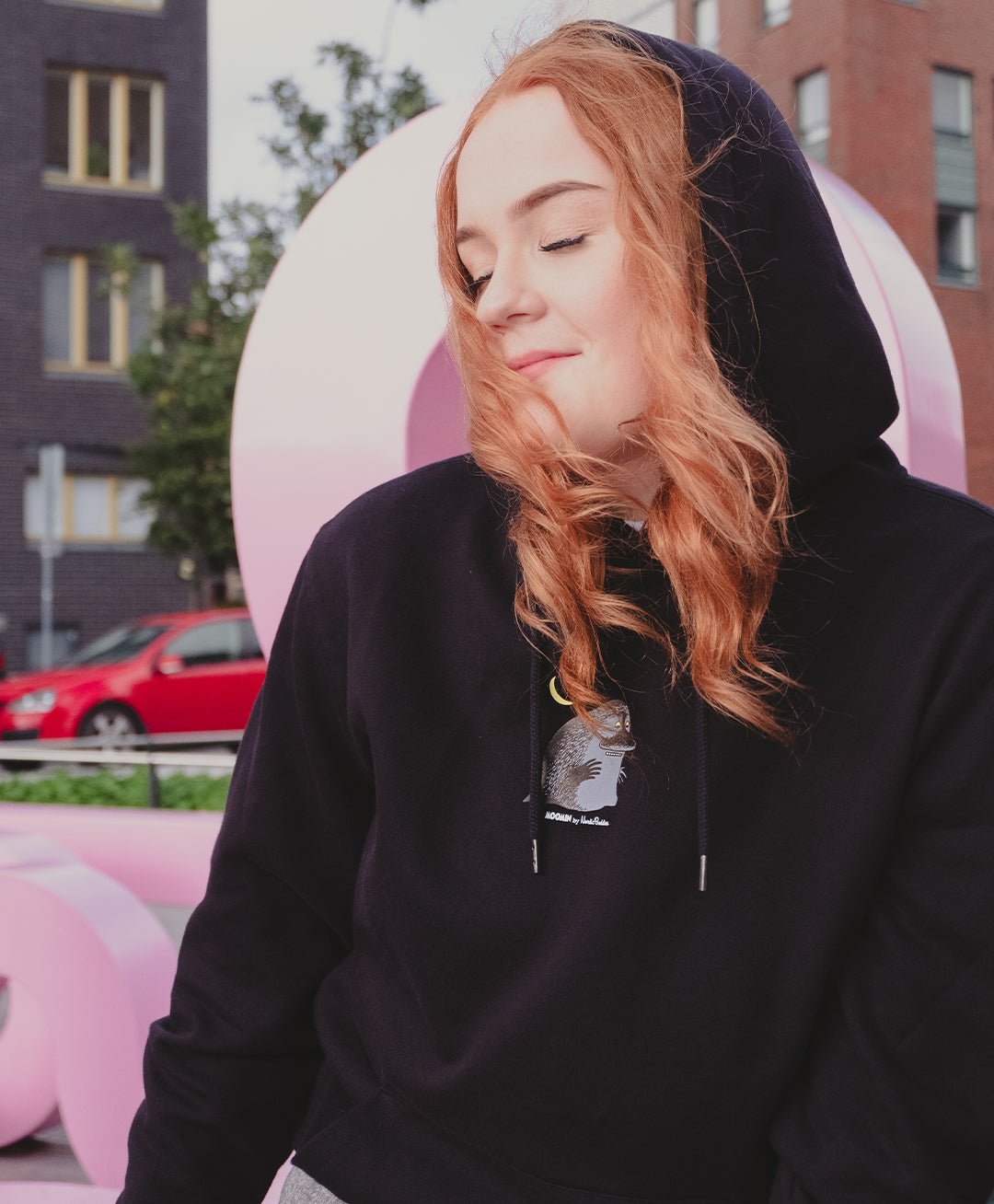 2. Unisex black Moomin hoodie worn by female model in urban setting, showcasing minimalistic character detail