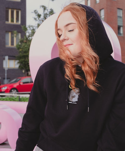2. Unisex black Moomin hoodie worn by female model in urban setting, showcasing minimalistic character detail