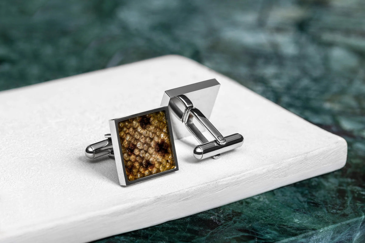 1. Square cufflinks made from yellow leather with black spots, featuring unique fish scale pattern, set in stainless steel, displayed on a white surface with a green marble background