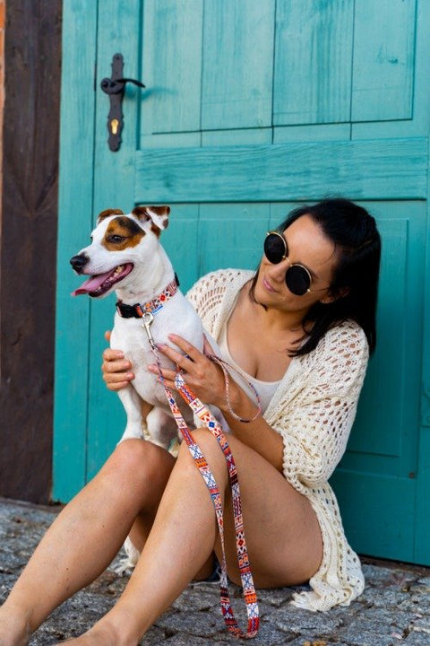 1. Woman sitting with dog wearing boho collar and leash in front of teal door