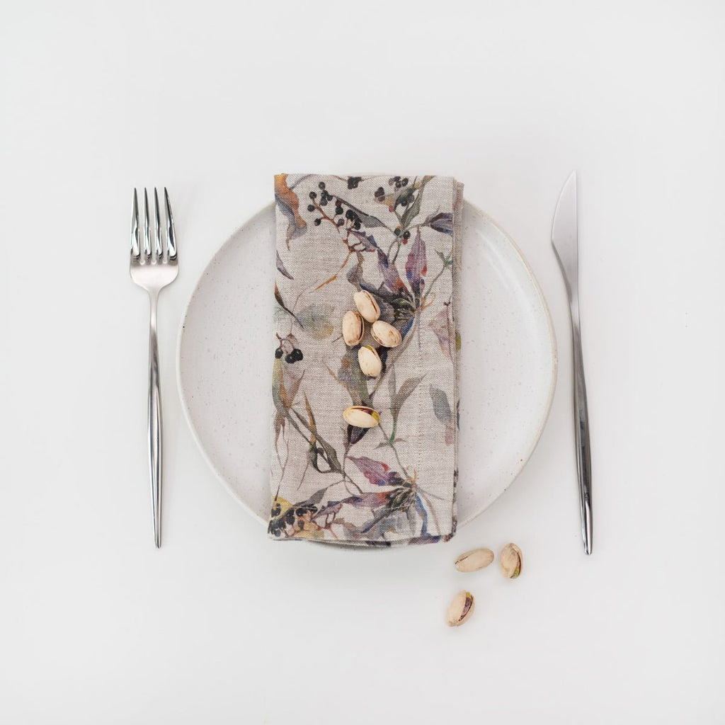 4. Floral linen napkin on a white plate with pistachios, accompanied by fork and knife
