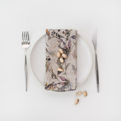 4. Floral linen napkin on a white plate with pistachios, accompanied by fork and knife