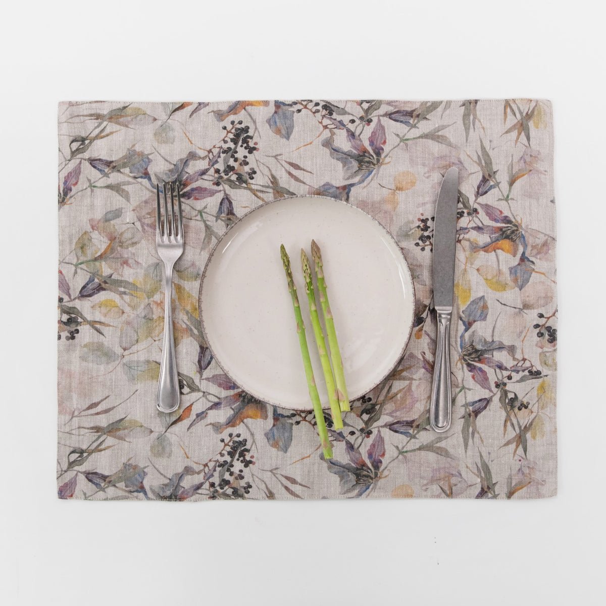 2. Botanical print linen placemat with asparagus on a white plate, set with a fork and knife
