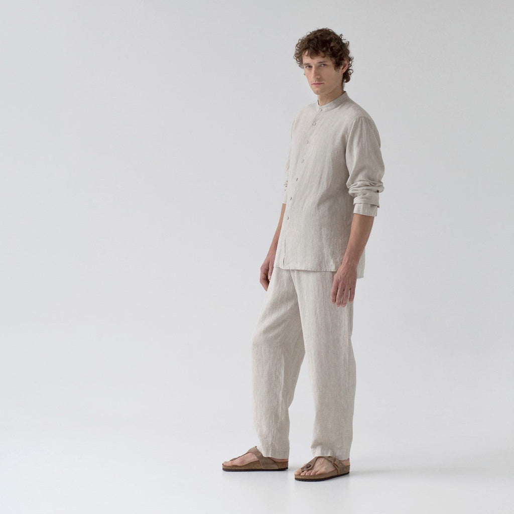 1. Man wearing beige linen loungewear set with long sleeves and buttoned front, standing in studio setting