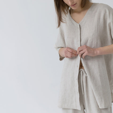 3. Close-up of woman buttoning melange linen loungewear top with drawstring pants