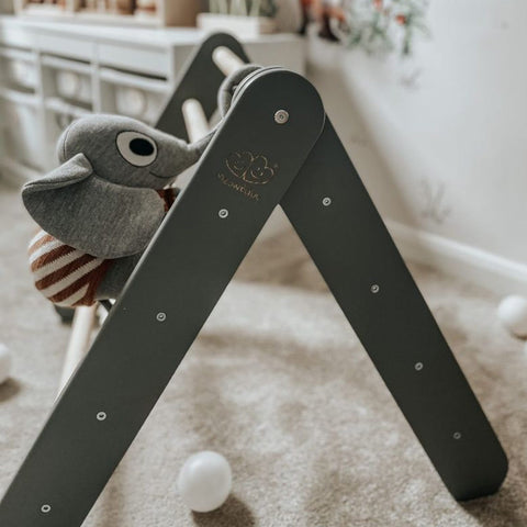 2. Gray wooden Pikler climbing ladder with a plush toy elephant on a carpeted floor
