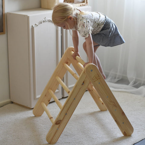 1. Child climbing small natural wood Pikler ladder in a living room setting