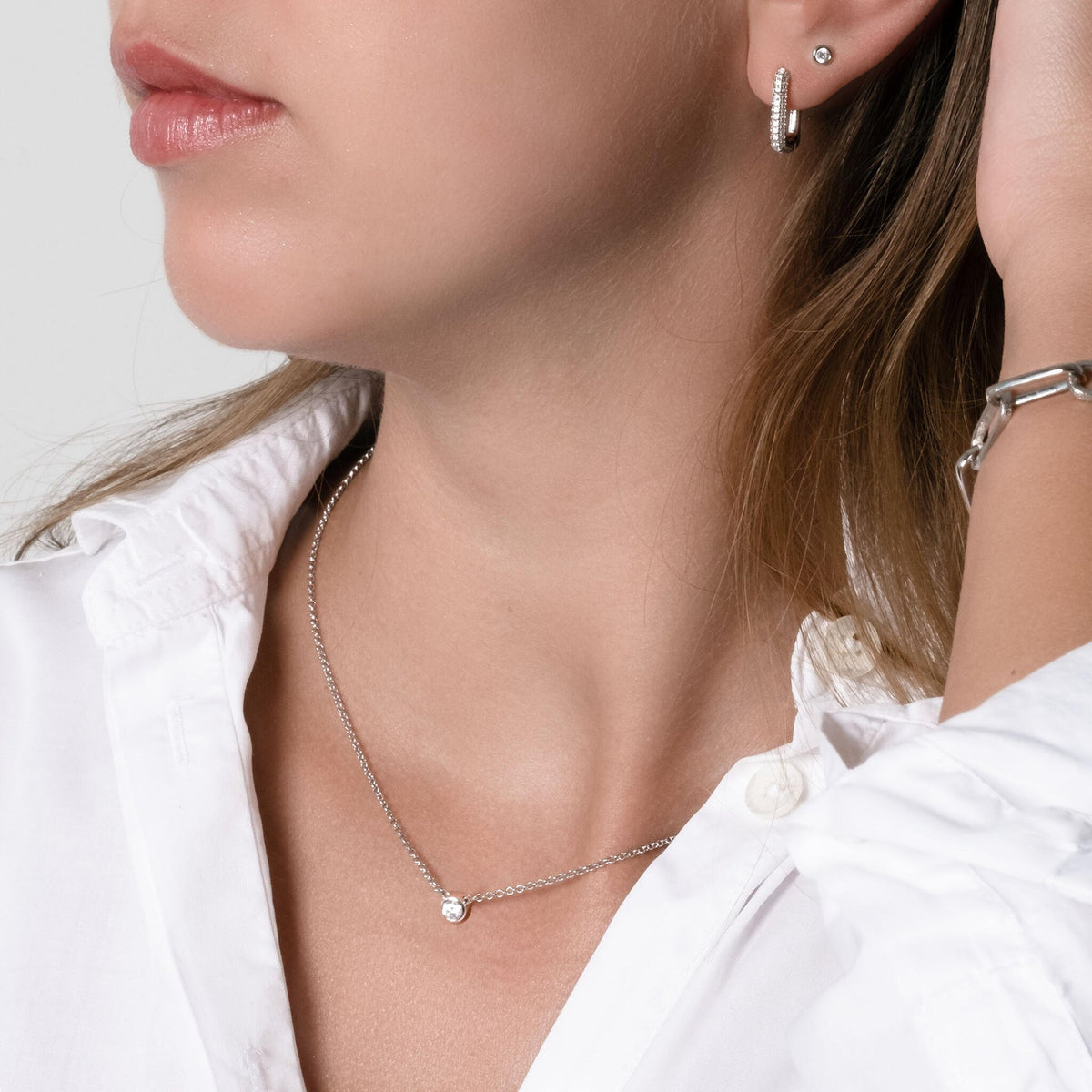 1. Woman wearing MyaMoon Illumi Choker in silver, styled with a white shirt, showcasing elegant zircon detail