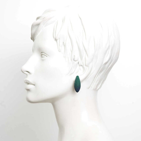 1. Mannequin wearing a single green Mini Avocados earring by Tanel Veenre, showcasing its elegant drop shape