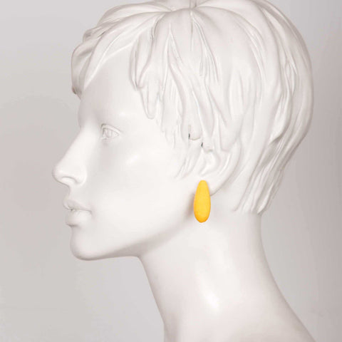 1. Side profile of a mannequin wearing Tanel Veenre Mini Bananas Earrings in yellow, highlighting the earring's length and vibrant color against a neutral background.