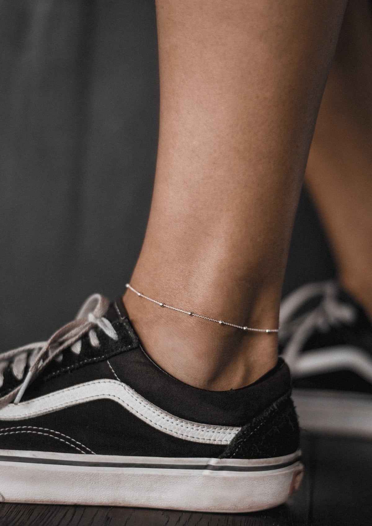 1. Women's Mini Bubble Anklet in sterling silver worn with black sneakers, showcasing minimalist summer style