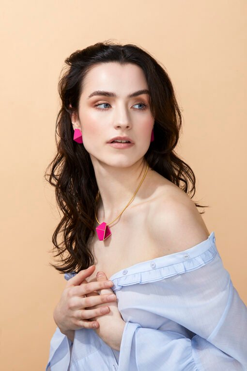 1. Woman wearing Lisa Kroeber Jewellery Folded Necklace in magenta, styled with matching earrings, lifestyle setting