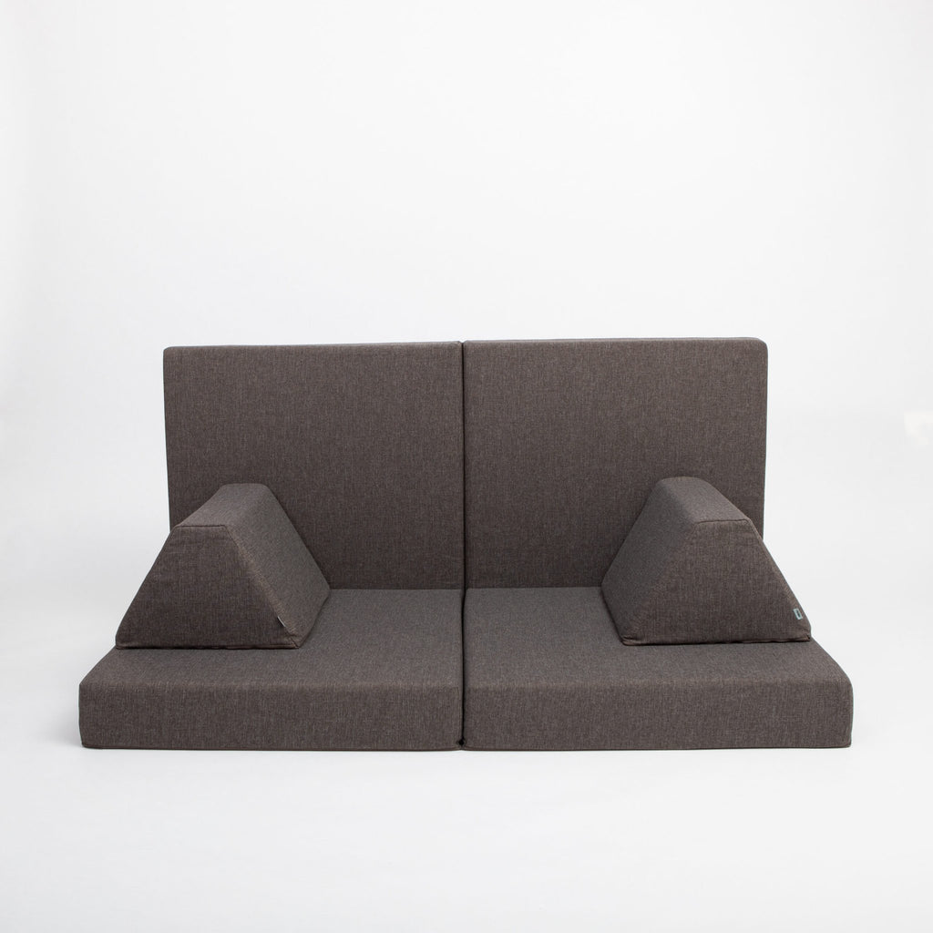 12. Monboxy dark brown play mattress set arranged as a sofa with trapezoidal pillows in a studio