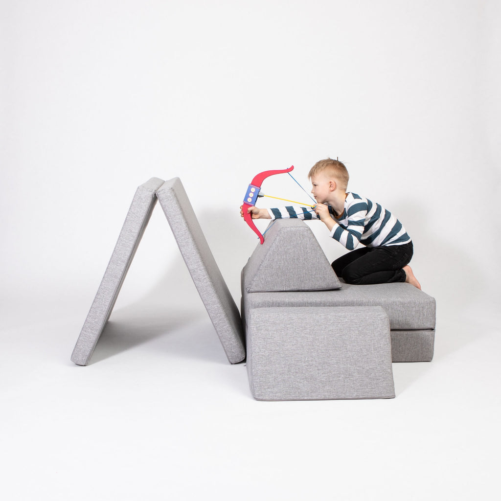 1. Child playing with bow and arrow on grey Monboxy activity play mattress set in studio