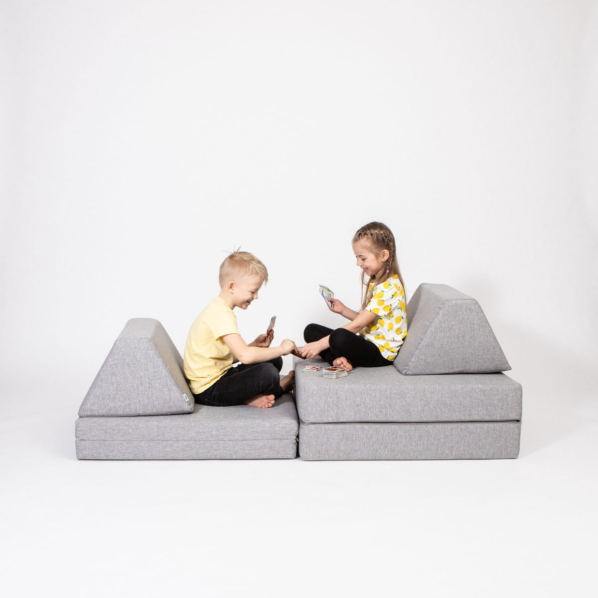 1. Two children playing on grey Monboxy activity play mattress set in studio