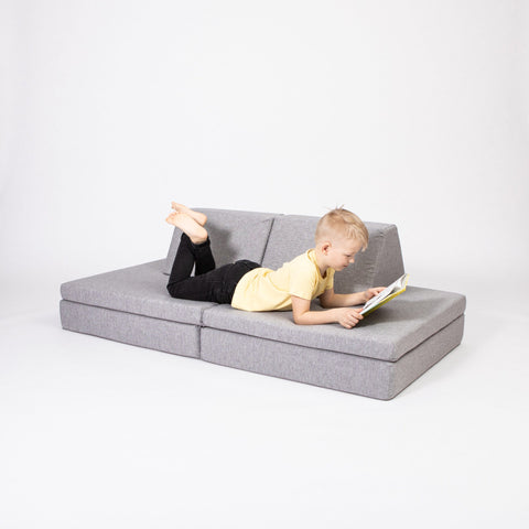 1. Child reading on grey Monboxy activity play mattress set in studio