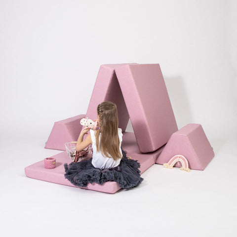 1. Girl playing with pink play mattress set arranged as a playhouse on a white background