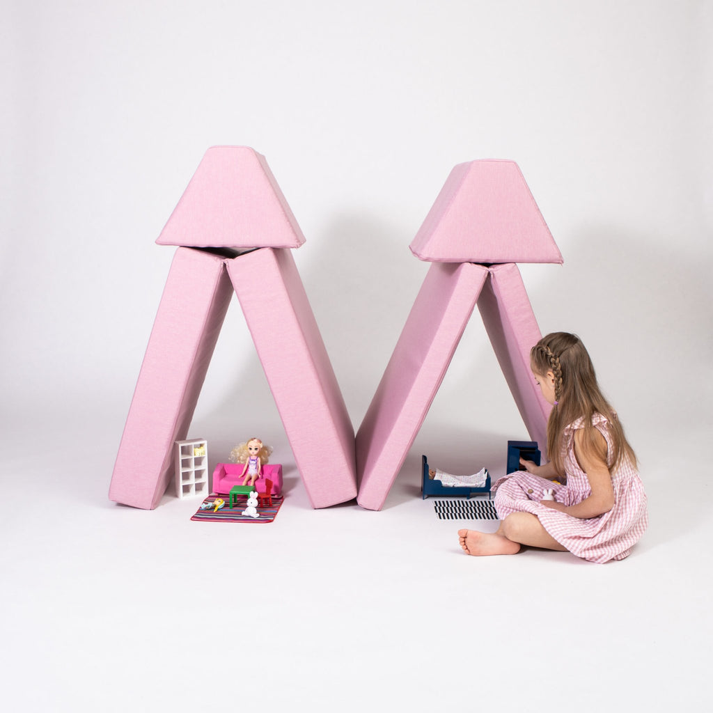 1. Girl playing with pink play mattress set arranged as tents on a white background