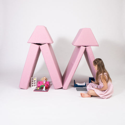 1. Girl playing with pink play mattress set arranged as tents on a white background