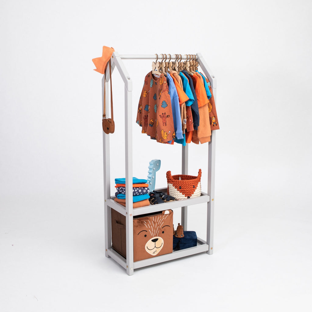 1. Grey house-shaped clothing rack with storage, featuring toddler clothes and accessories, on a white background