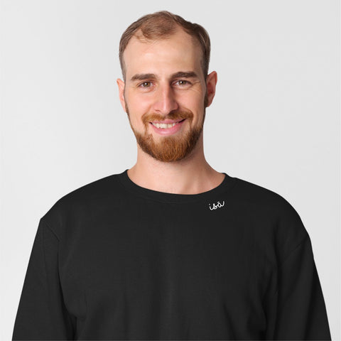 1. Unisex black organic cotton sweatshirt with 'Isä' embroidery worn by male model in studio