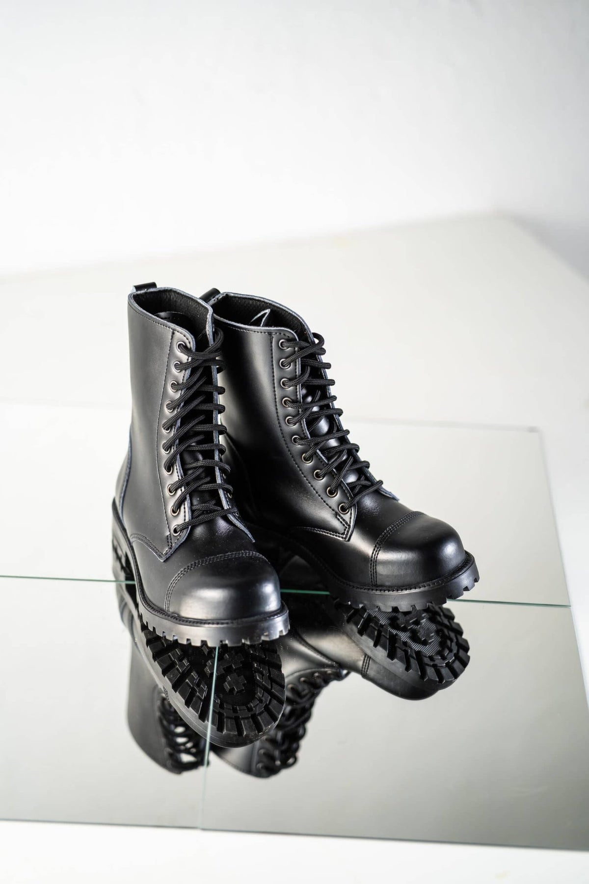 4. Pair of Samelin 511 Black boots on reflective surface, emphasizing rugged sole and leather finish