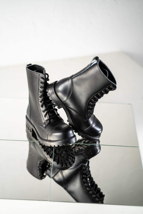 5. Samelin 511 Black boots on reflective surface, one boot tilted to show sole pattern