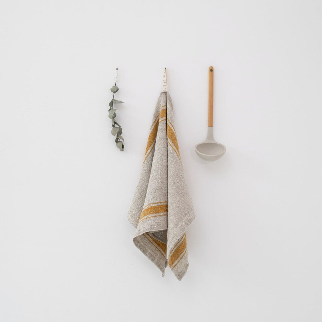 3. Beige linen kitchen towel with mustard stripes hanging on white wall with ladle