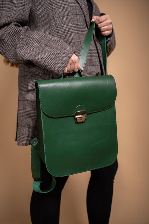 5. Woman holding Zelma Kraft green leather saddle backpack, emphasizing front clasp and design