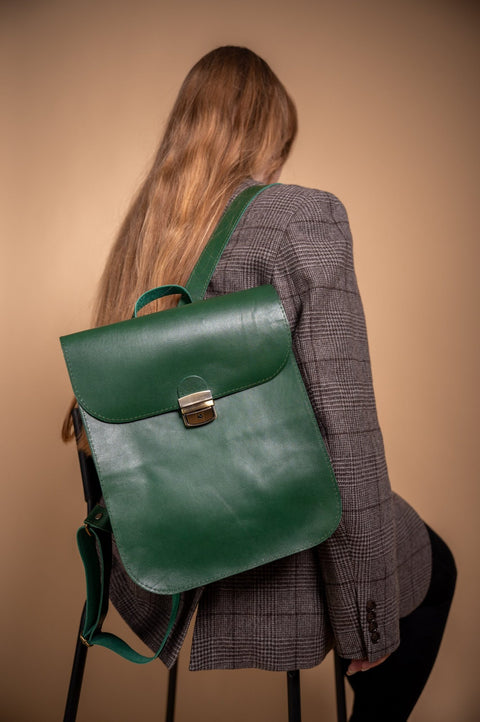 1. Woman wearing Zelma Kraft green leather saddle backpack, shown from the back in lifestyle setting