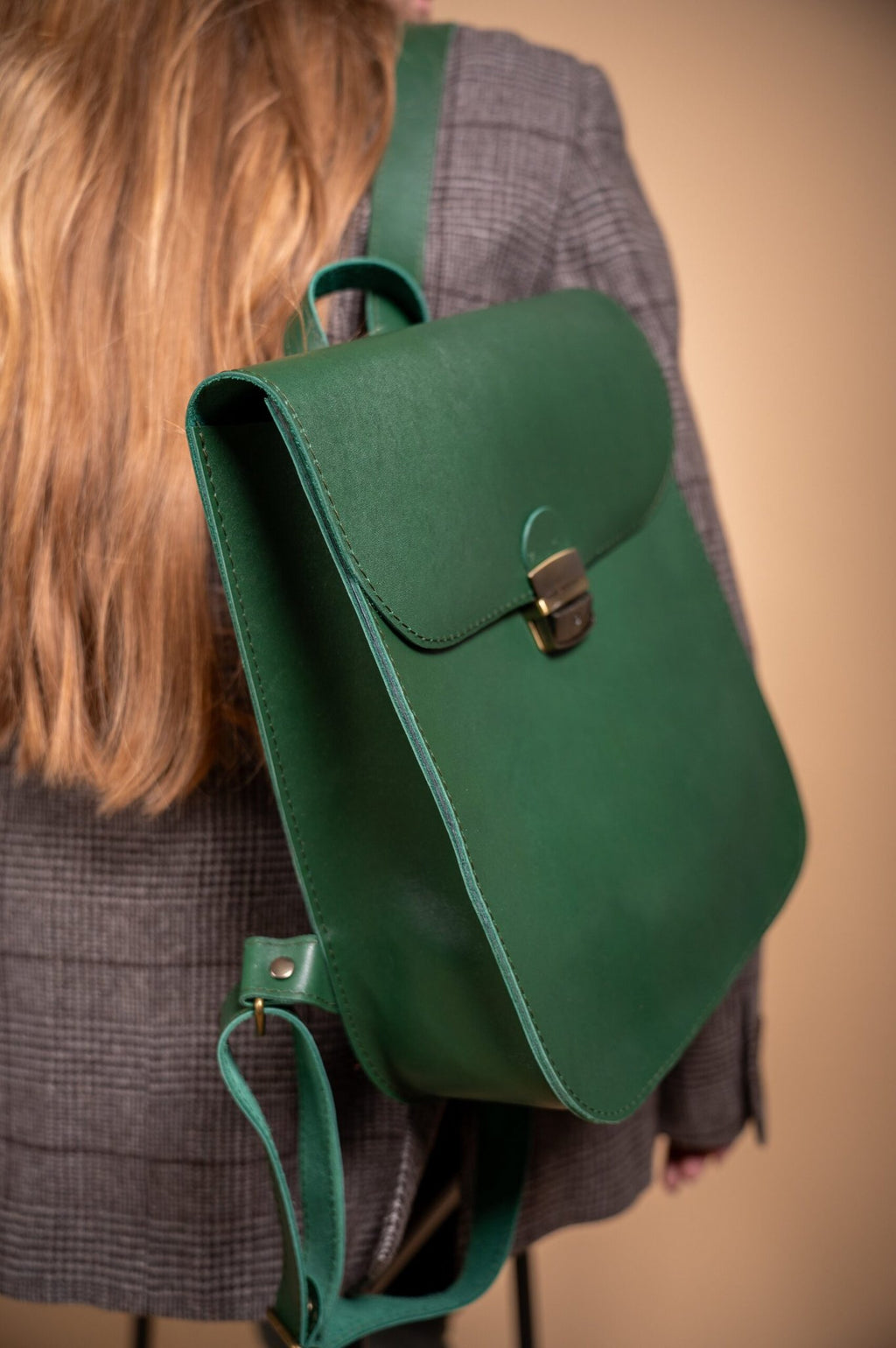 4. Close-up of Zelma Kraft green leather saddle backpack, highlighting adjustable straps and side view