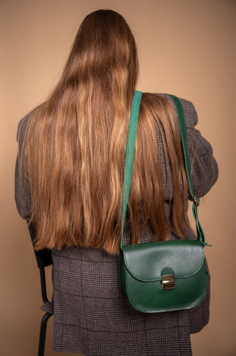 2. Woman wearing Zelma Kraft green leather saddle bag over shoulder, shown from the back