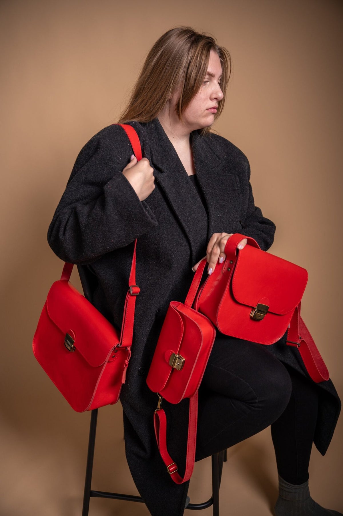 1. Women's red leather saddle bags by Zelma Kraft, styled with black coat in lifestyle setting