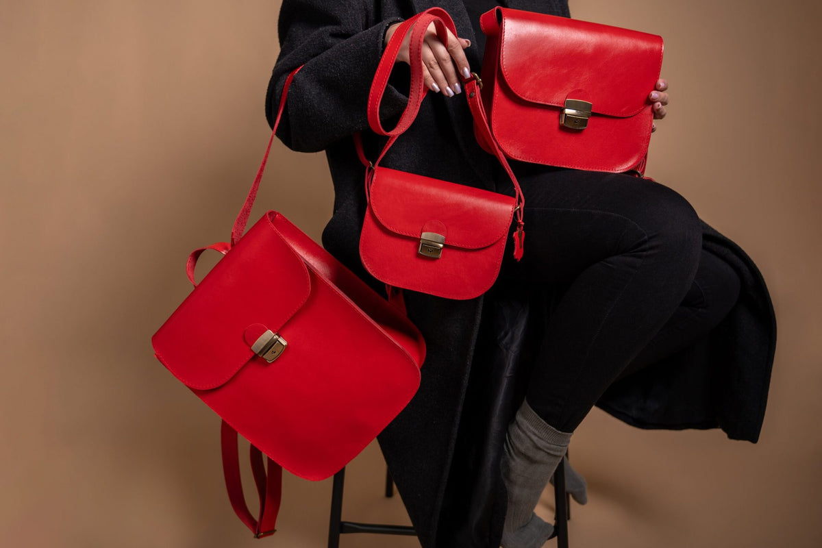 4. Studio image of Zelma Kraft red natural leather saddle bag, showing front view with buckle closure
