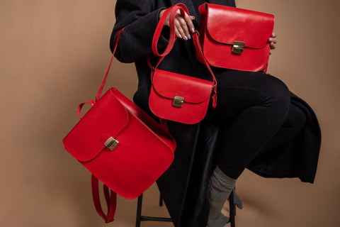 4. Studio image of Zelma Kraft red natural leather saddle bag, showing front view with buckle closure