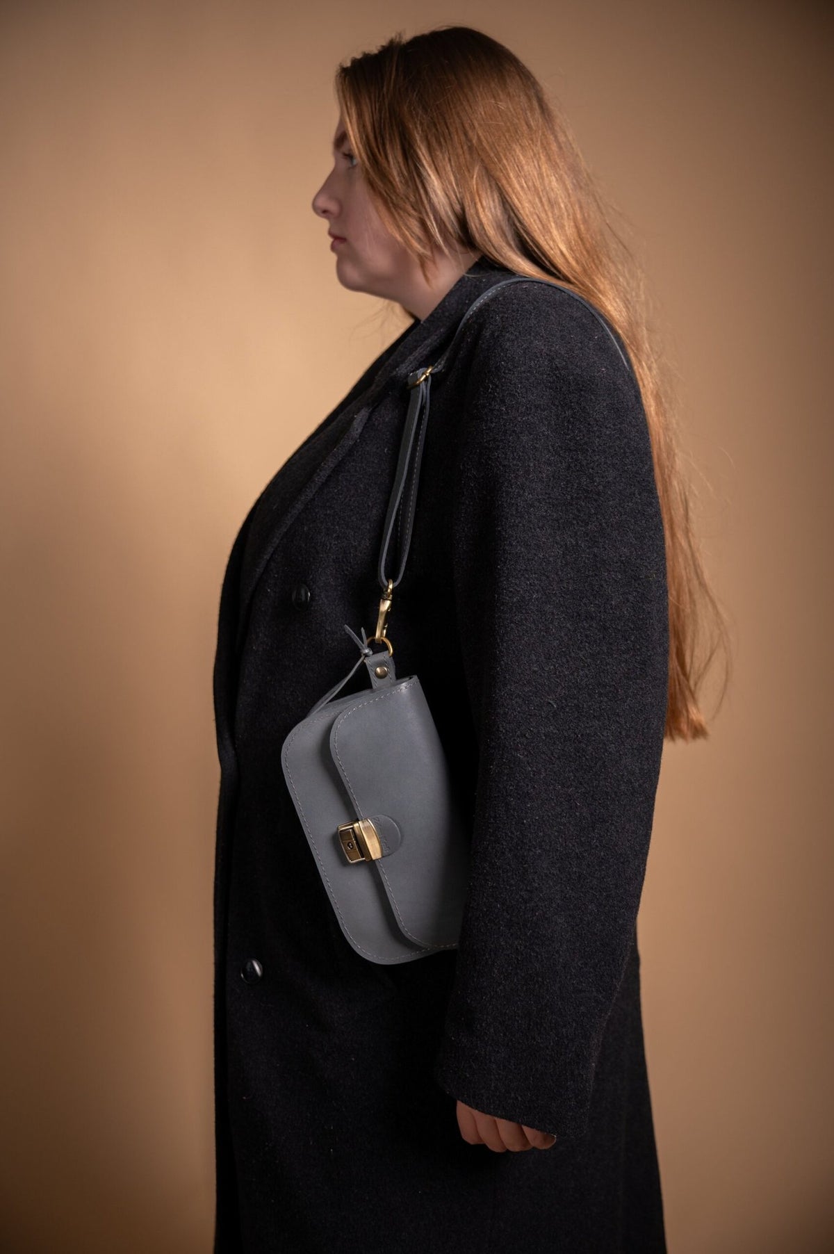 2. Side view of women's grey leather saddle bag mini by Zelma Kraft, worn over shoulder with adjustable strap