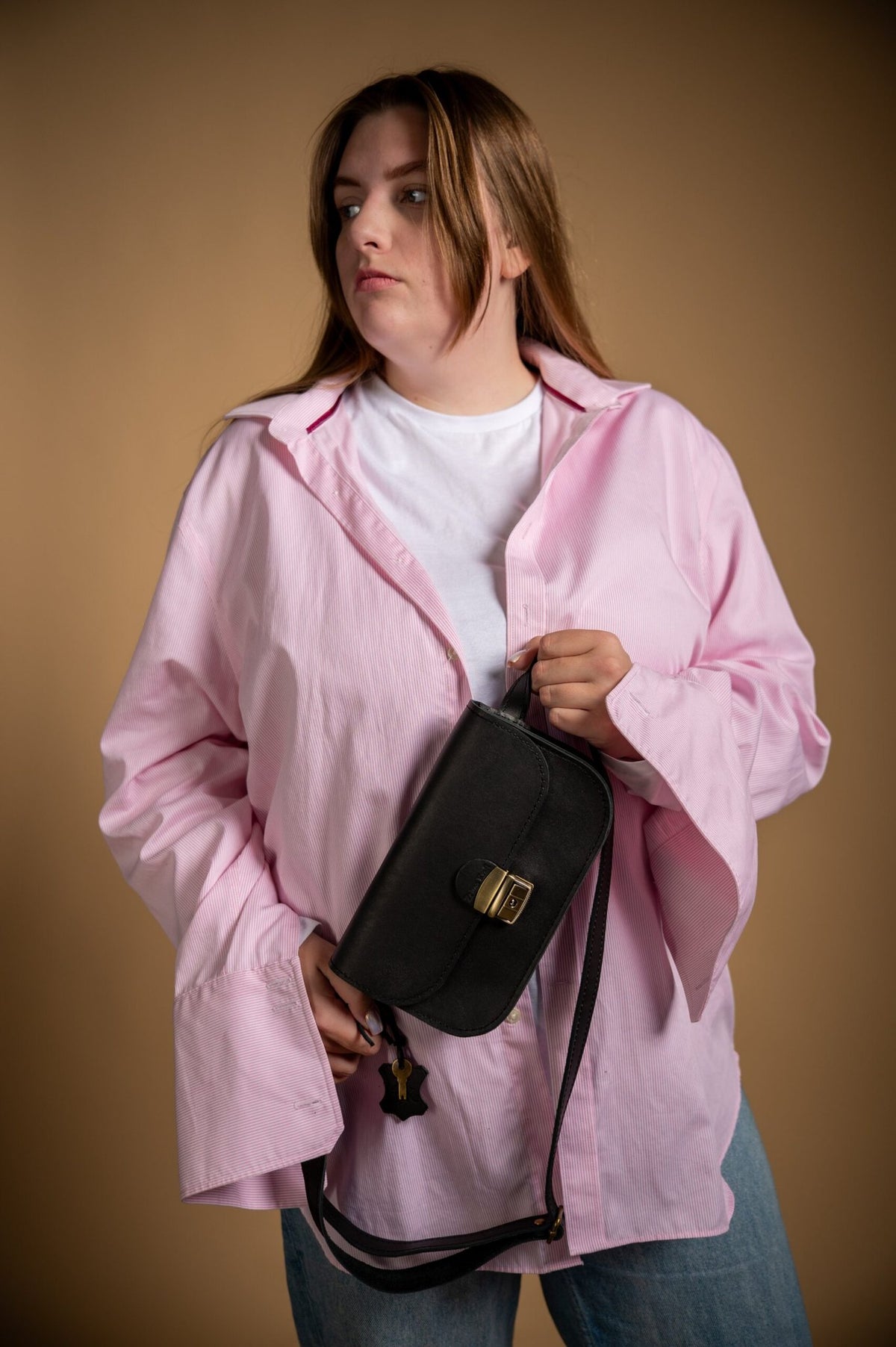 2. Woman wearing black Zelma Kraft leather saddle bag mini with adjustable strap