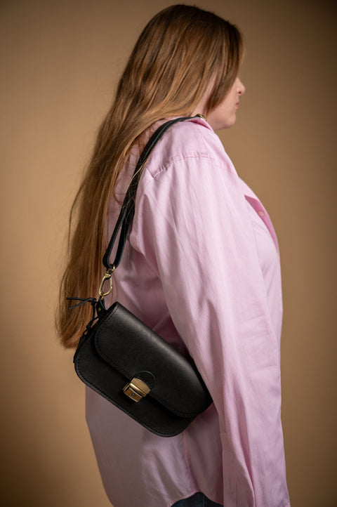 3. Side view of woman with black Zelma Kraft leather saddle bag mini over shoulder